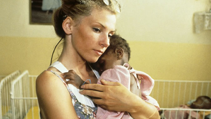 Una trabajadora humanitaria lleva a un bébé en brazo