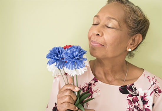 Mujer adulta ayor oliendo flores