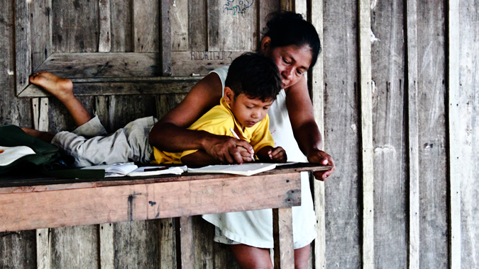 A woman helps her child to make his homework.